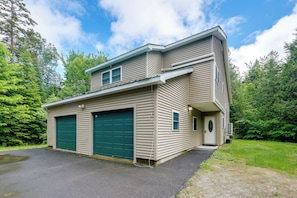 Une maison à deux étages avec un garage, une véranda et une allée.