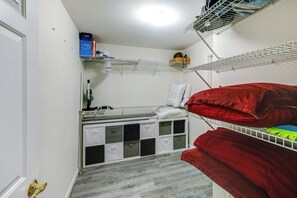 A compact room with a bunk bed, a small desk, and storage drawers.