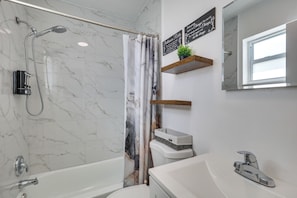 Une salle de bain avec une douche, un lavabo, un miroir et une fenêtre.