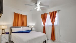 A bedroom with a bed, nightstand, lamp, ceiling fan, and curtains. - Close to Hard Rock Stadium! Group Getaway w/ Yard (Miami Gardens)