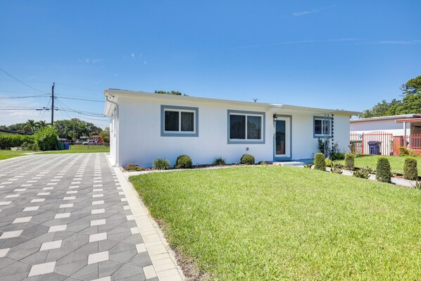 A single-story house with a front lawn, a paved driveway, and a small garden area.