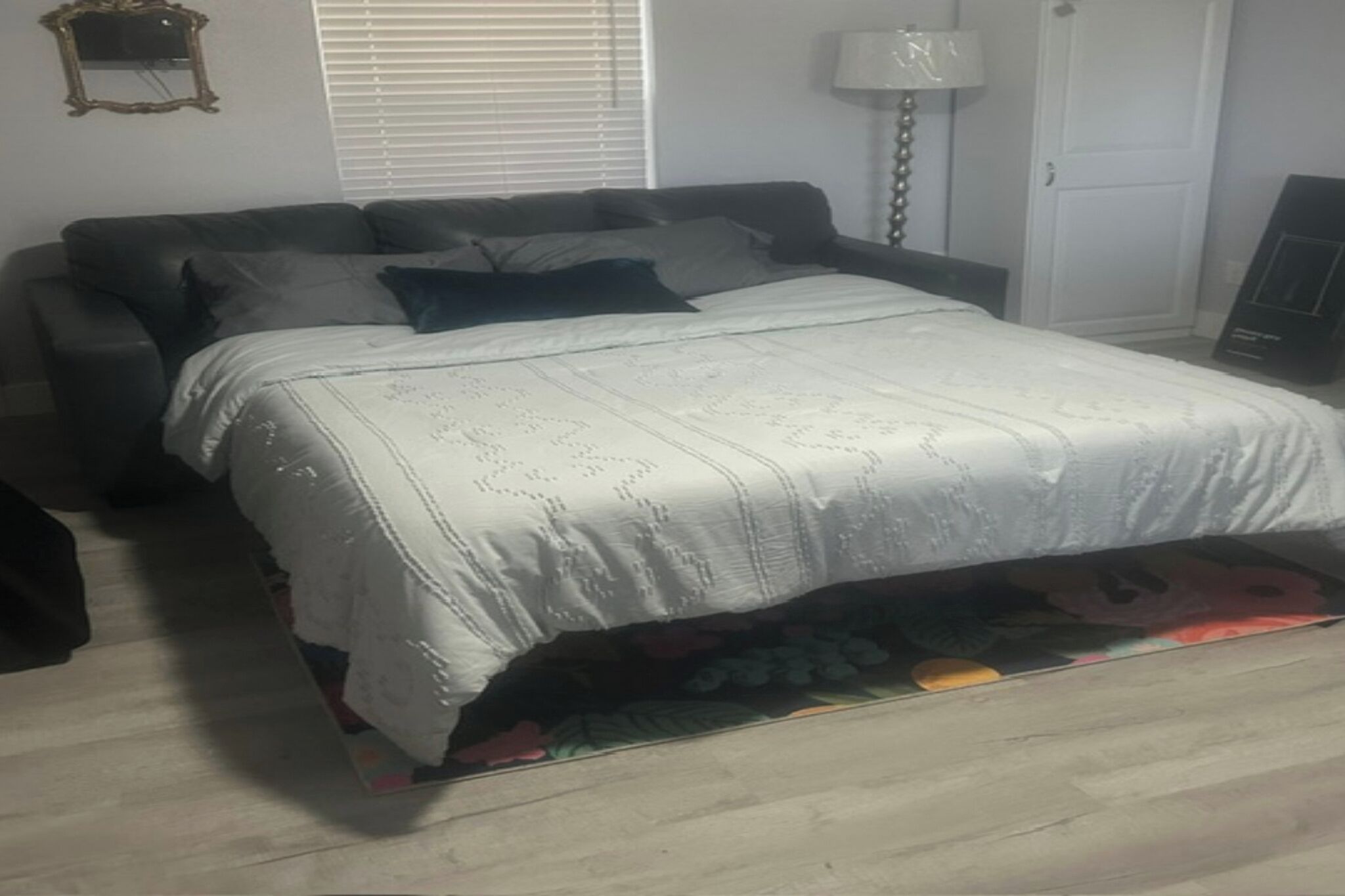 Un dormitorio con cama, sofá, lámpara y espejo.