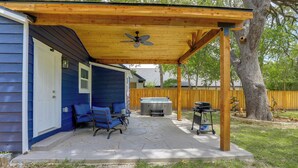 Un patio couvert avec un ventilateur de plafond, un jacuzzi et un espace barbecue.
