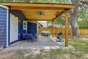 A covered patio with a ceiling fan, a hot tub, and a grill area.