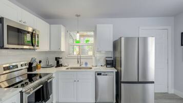A modern kitchen with stainless steel appliances, white cabinetry, and a dishwasher.