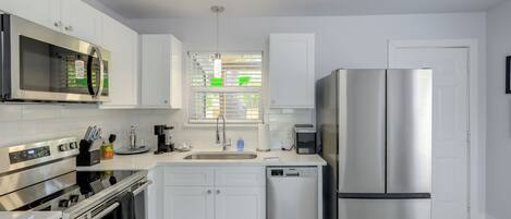 A modern kitchen with stainless steel appliances, white cabinetry, and a dishwasher.