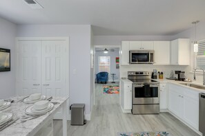A modern kitchen with white cabinets, stainless steel appliances, and a marble countertop. - New On The Market - Hot Tub, 1 Block to Square (Granbury)
