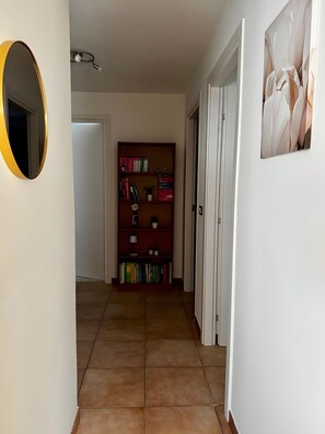 Ein Flur mit Bücherregal, Spiegel und einer Tür zu einem anderen Raum.