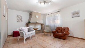 Ein Wohnzimmer mit Kamin, zwei Sesseln, einer Couch und Kunstwerken an den Wänden.