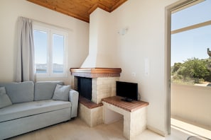 A room with a sofa, a television, and a fireplace. - Secret Beach A Apartment with Sea View, Wi-Fi, and Air Conditioning (Nikiana)