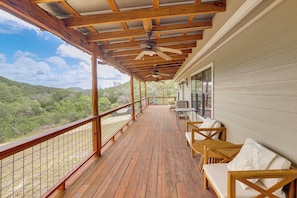 A wooden deck with outdoor seating, a ceiling fan, and a view of the surrounding landscape. - Horse Friendly! Hill Country Retreat w/ Views (Tarpley)