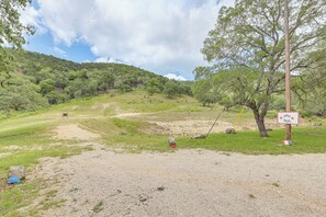 A rural landscape with a dirt path leading to a chair, a sign indicating a trail, and a tree. - Horse Friendly! Hill Country Retreat w/ Views (Tarpley)