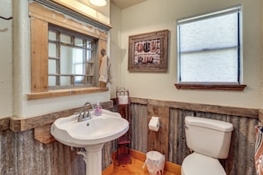 A bathroom with a wooden vanity, a sink, a toilet, and a window. - Horse Friendly! Hill Country Retreat w/ Views (Tarpley)