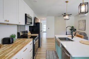 A modern kitchen with white cabinets, a black refrigerator, a microwave, and a wooden countertop. - Close to Dtwn & Med Center: Knoxville Home Base (Knoxville)