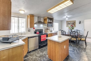 A kitchen with wooden cabinets, a stove, a microwave, and a dining area with chairs.