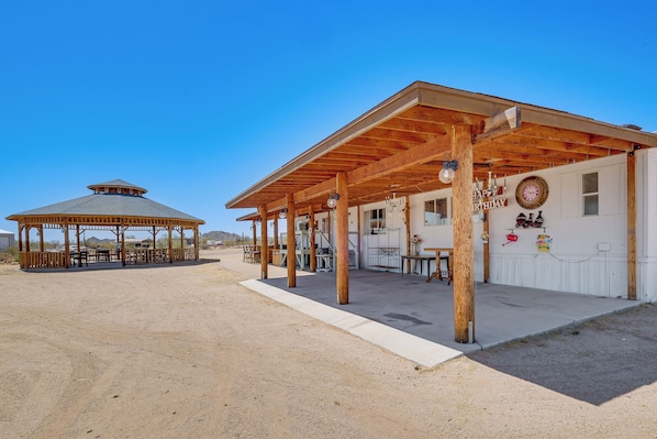 A covered outdoor area with a wooden pavilion and a building with a 'Happy Birthday' sign.