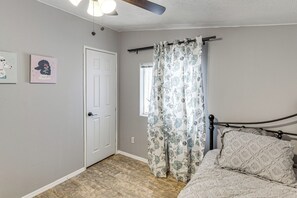 Une chambre à coucher avec un lit, une porte, une fenêtre et un ventilateur de plafond.