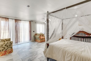 A bedroom with a four-poster bed, a sofa, and a chair.