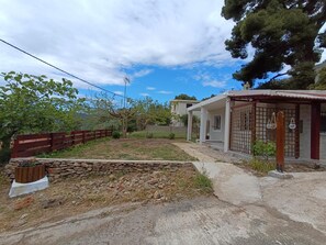 Una propiedad residencial con un muro de piedra, una valla de madera y un porche cubierto.