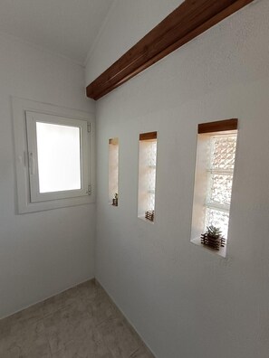 Una habitación con un ventanal grande, tres ventanas más pequeñas y una viga de techo de madera.