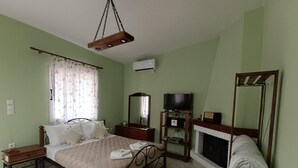 Un dormitorio con cama, mesitas de noche, televisión, espejo y chimenea.