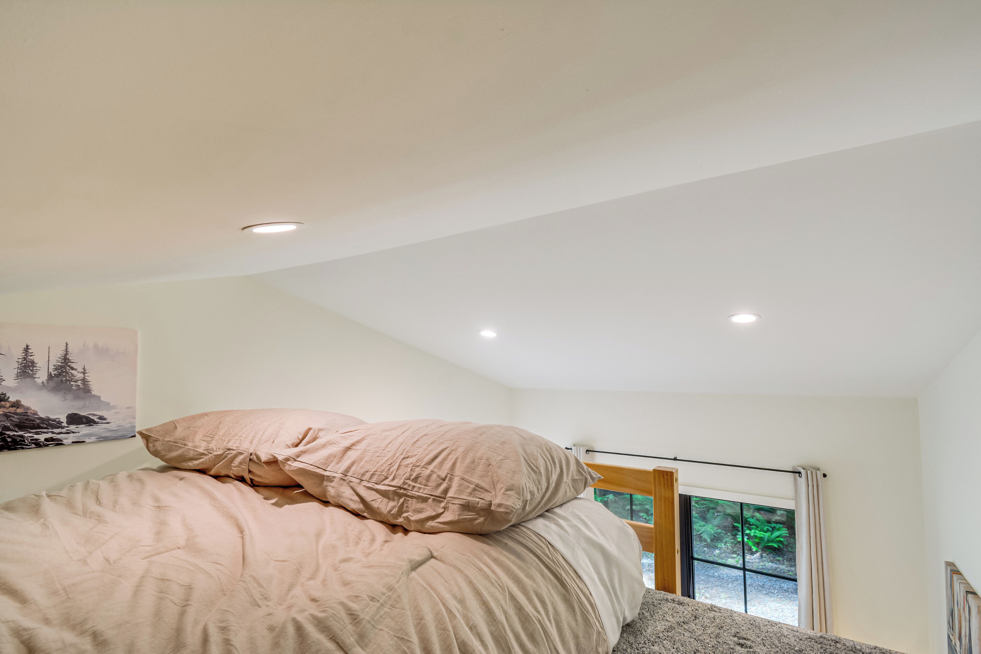Een slaapkamer met een bed, een raam met uitzicht en een schilderij aan de muur.