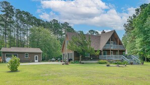 A two-story cabin with a front deck and a garage. - 10-acre Retreat w/ Hiking! Gateway to Holden Beach (Shallotte)