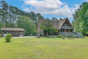 A two-story cabin with a front deck and a garage. - 10-acre Retreat w/ Hiking! Gateway to Holden Beach (Shallotte)