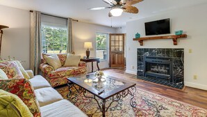 A living room with a sofa, a coffee table, a fireplace, a television, and a ceiling fan. - 10-acre Retreat w/ Hiking! Gateway to Holden Beach (Shallotte)
