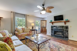 Ein Wohnzimmer mit einer Couch, einem Couchtisch, einem Kamin, einem Fernseher und einem Deckenventilator.