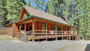 A log cabin with a porch, wooden steps, and a flag. - Forest, Fairways, Lake Almanor Days! Lake Love (Westwood)