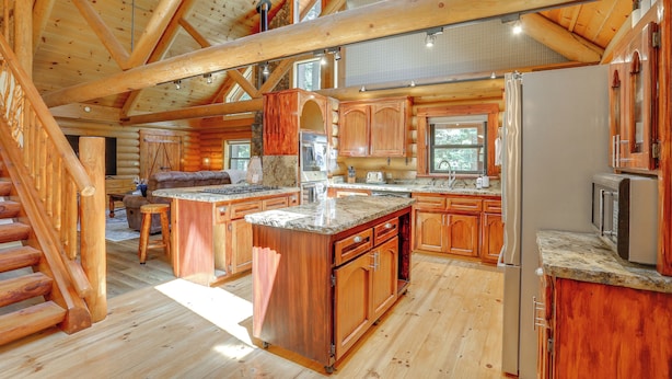 A spacious log cabin interior with a large kitchen, wooden staircase, and a cozy living area. - Forest, Fairways, Lake Almanor Days! Lake Love (Westwood)