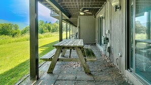 Un patio techado con una mesa de picnic, un ventilador de techo y vistas al exterior.