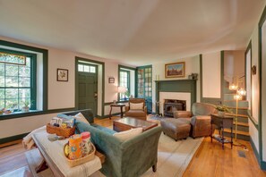 A cozy living room with a fireplace, comfortable seating, and a view of the outdoors.