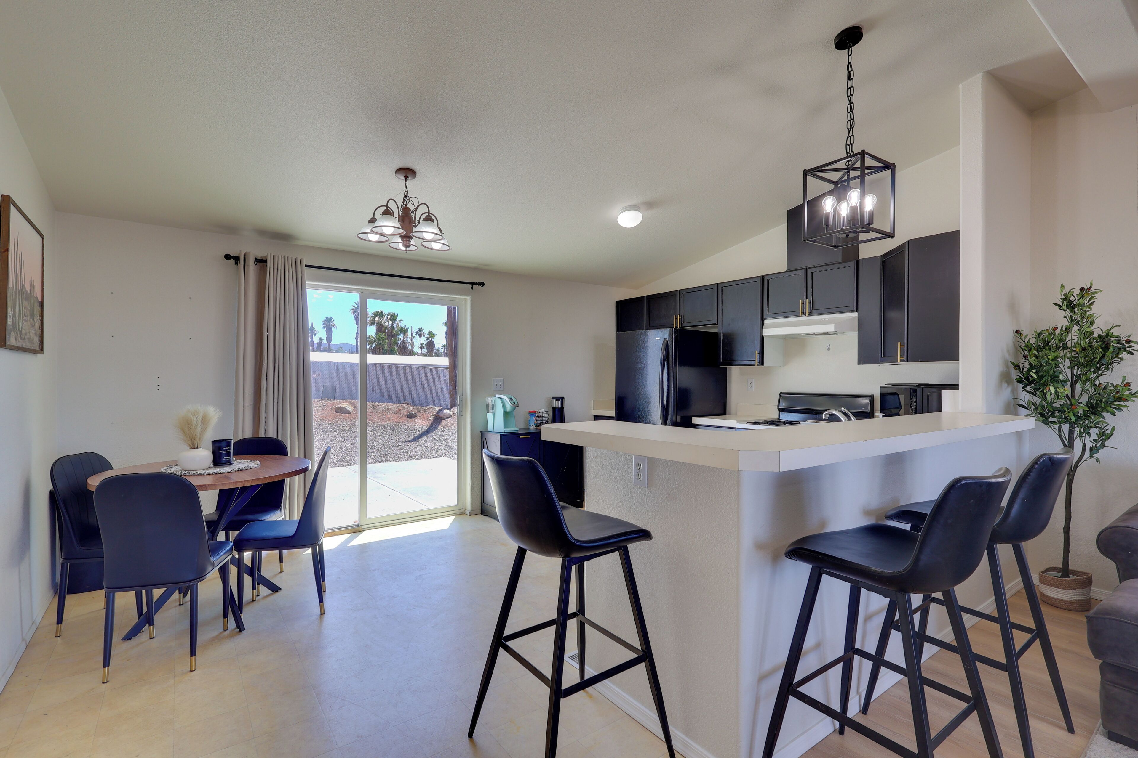 A modern kitchen with a central island, bar stools, and a dining area with chairs.