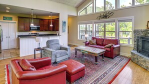 A spacious living area with a fireplace, a kitchen with wooden cabinets, and large windows. - Asheville Mountain Hideaway, 6 Mi to Dtwn (Asheville)