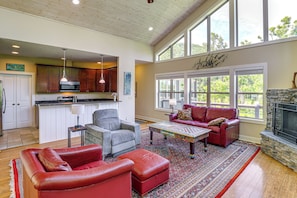 A spacious living area with a fireplace, a kitchen in the background, and large windows. - Asheville Mountain Hideaway, 6 Mi to Dtwn (Asheville)
