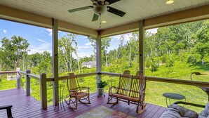 A covered porch with wooden flooring, rocking chairs, a small table, and a view of a green landscape. - Asheville Mountain Hideaway, 6 Mi to Dtwn (Asheville)