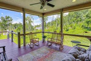 A covered porch with wooden flooring, rocking chairs, a small table, and a view of a green landscape. - Asheville Mountain Hideaway, 6 Mi to Dtwn (Asheville)