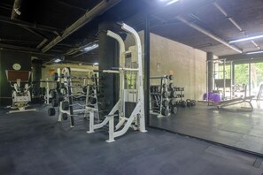A gym with weightlifting equipment, a clock on the wall, and a large window. - Resort Living in Tulum! Walkable Downtown Condo (Tulum)