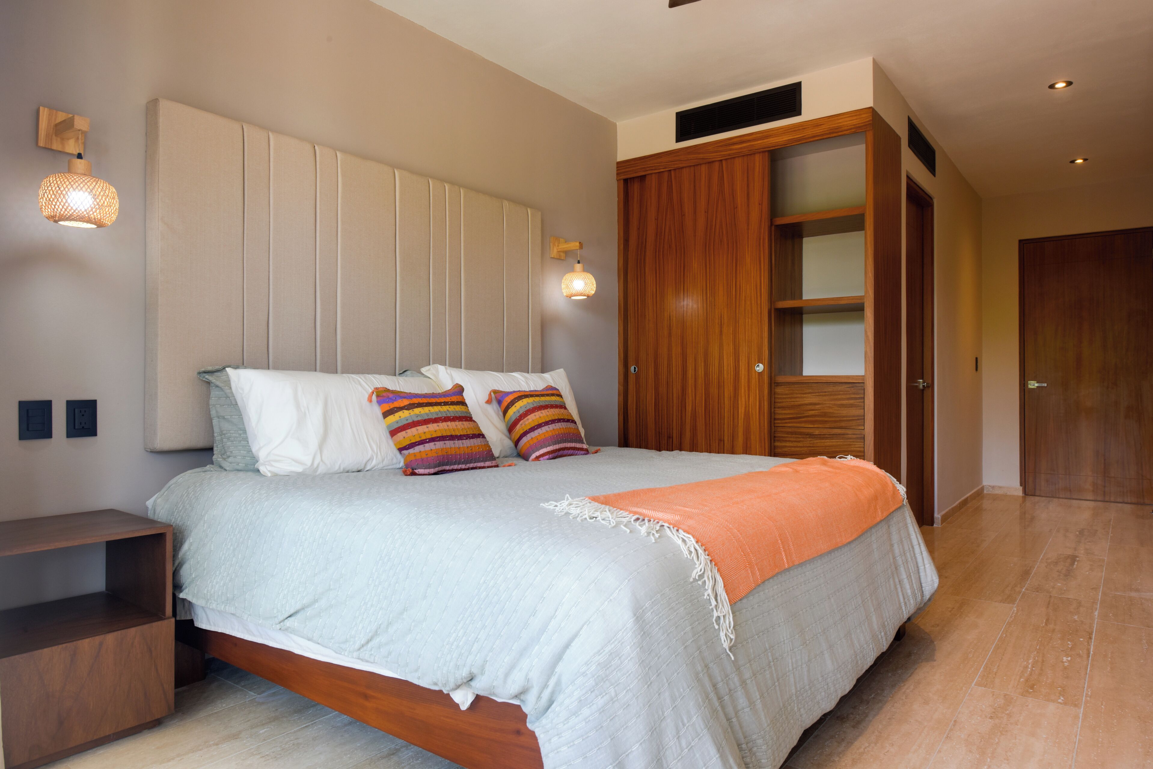 A bedroom with a bed, wooden wardrobe, and a nightstand.
