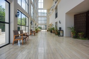 A spacious indoor area with large windows, wooden chairs, and potted plants. - Resort Living in Tulum! Walkable Downtown Condo (Tulum)