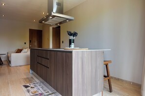 A modern kitchen with a central island, wooden cabinets, and a stainless steel range hood. - Resort Living in Tulum! Walkable Downtown Condo (Tulum)