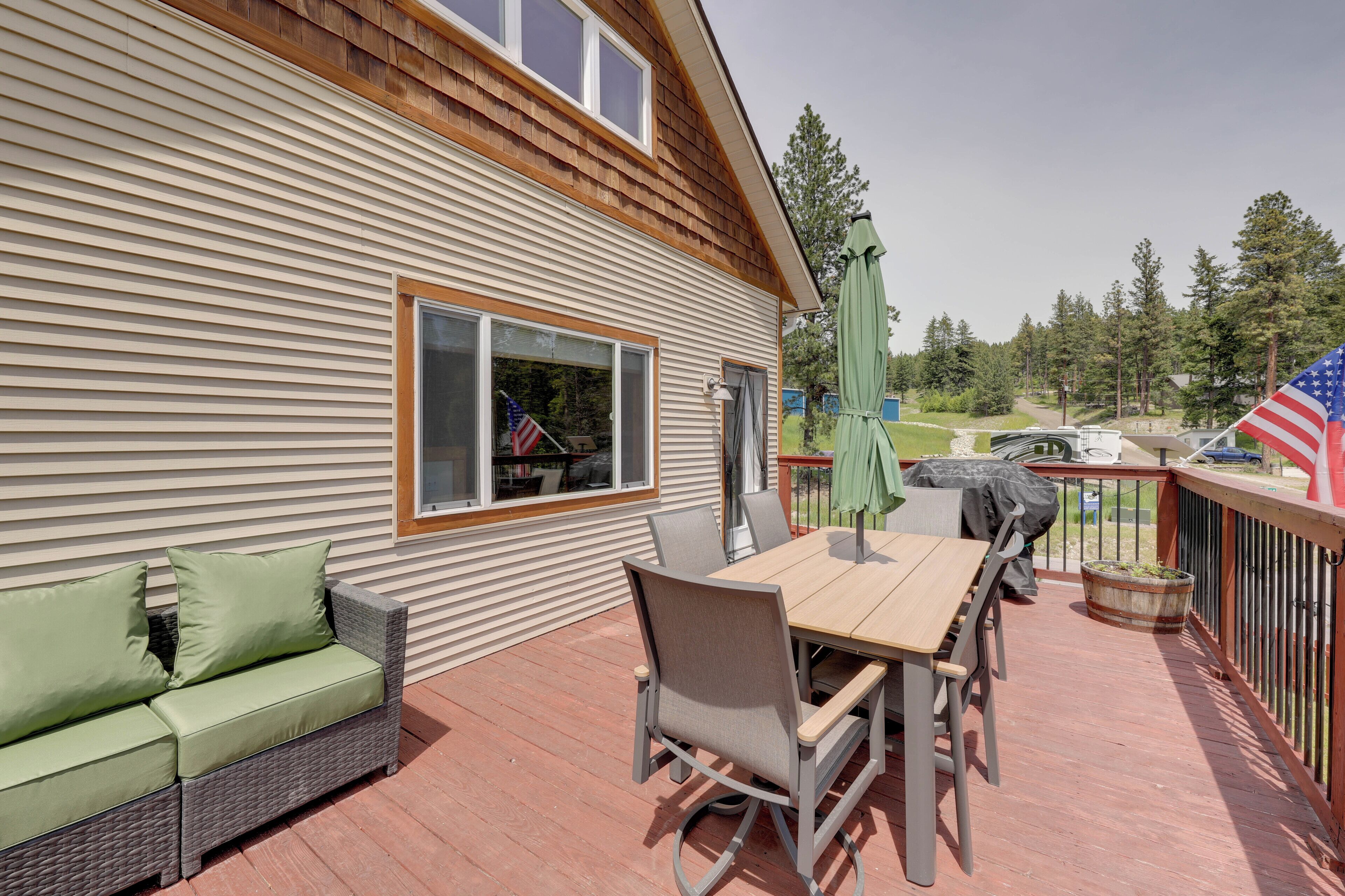 A deck with a table and chairs, a sofa, and an American flag.