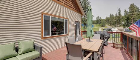 A deck with a table and chairs, a sofa, and an American flag.