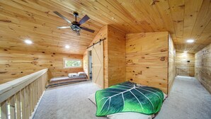 Ein Holzblockhaus-Interieur mit einem Bett, einem Deckenventilator und einem Fenster.