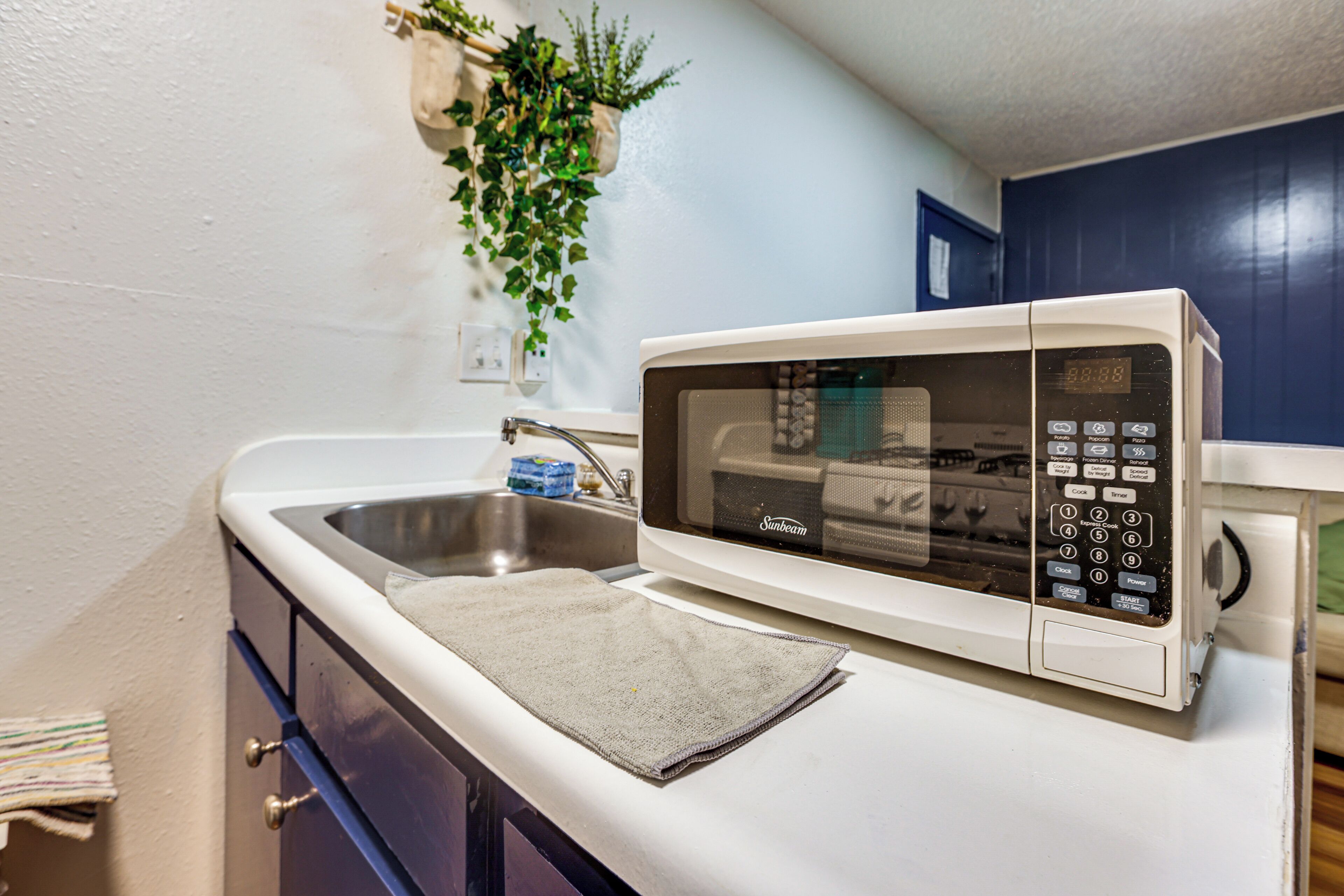 A kitchen with a microwave, a sink, and a towel on the counter.