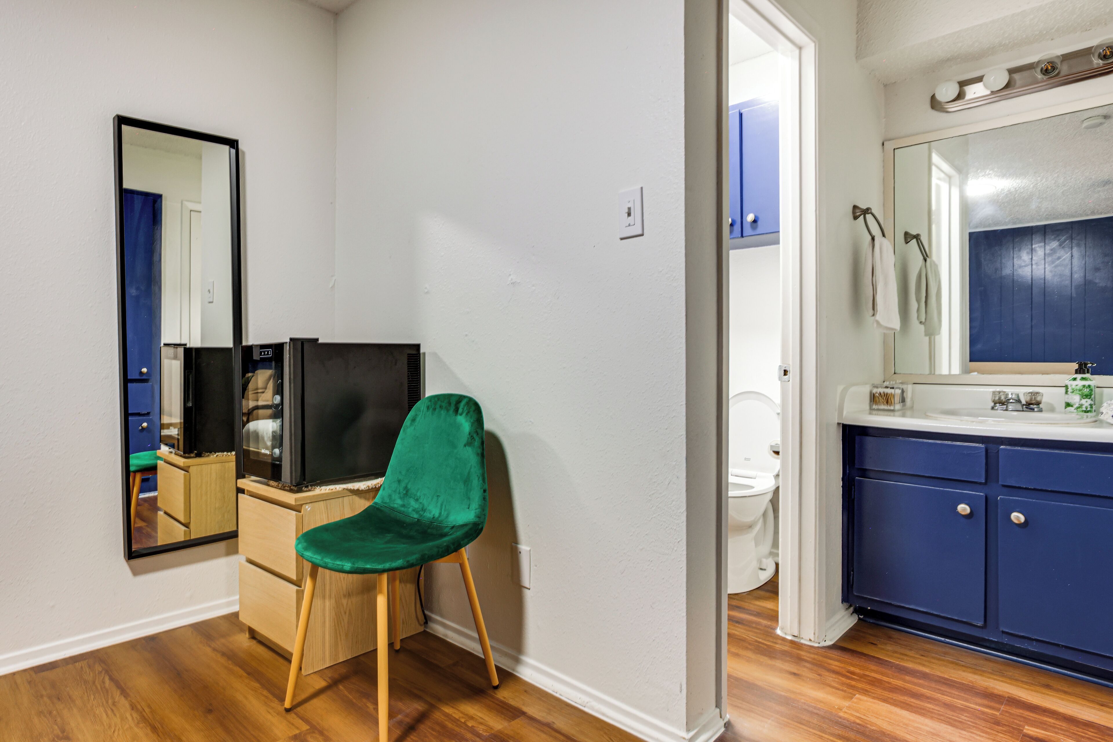 Une petite salle de bain comprenant des toilettes, un lavabo, un miroir et une chaise verte.