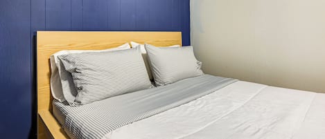 A bed with a wooden headboard, white bedding, and striped pillows.
