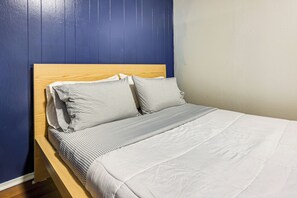 Ein Bett mit Holz-Kopfteil, weißer Bettwäsche und gestreiften Kissen.